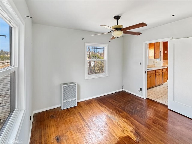 empty room with ceiling fan, heating unit, and light hardwood / wood-style flooring