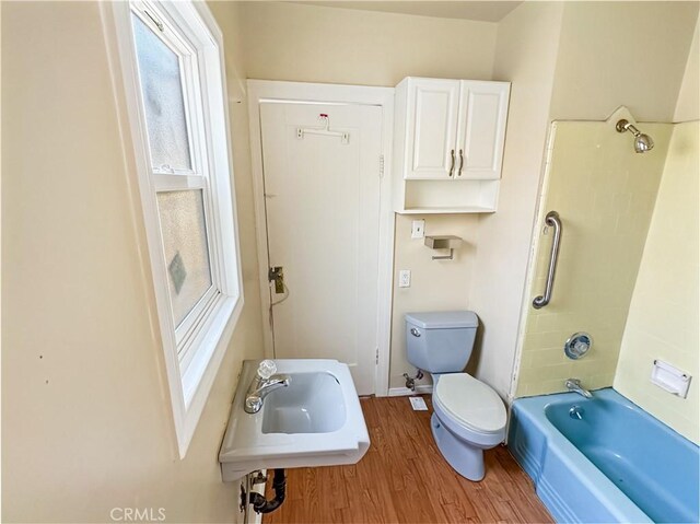 full bathroom with toilet, wood-type flooring, tub / shower combination, and sink