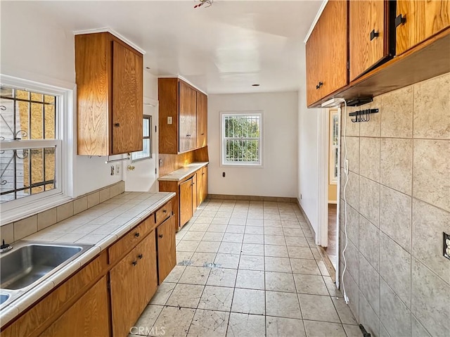 kitchen with light tile patterned flooring, tile counters, and sink