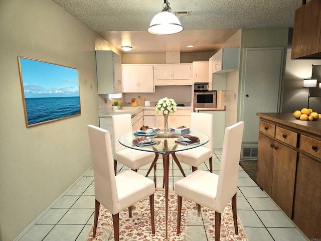 tiled dining room featuring sink, a textured ceiling, and a water view