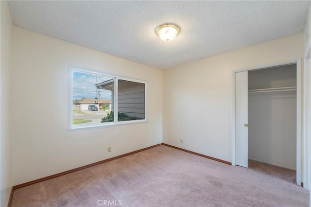 unfurnished bedroom with light colored carpet, a textured ceiling, and a closet