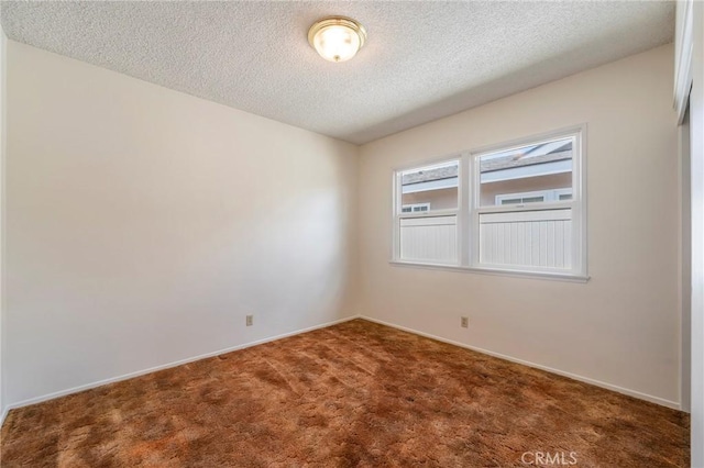 carpeted empty room featuring a textured ceiling