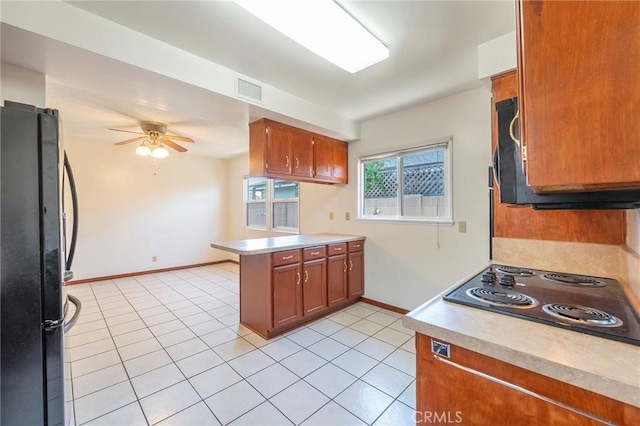 kitchen with light tile patterned flooring, stainless steel fridge, kitchen peninsula, ceiling fan, and black electric stovetop