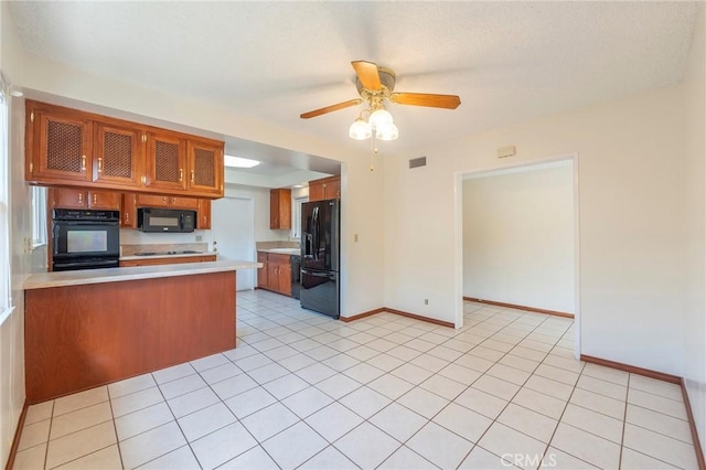 kitchen featuring light tile patterned flooring, kitchen peninsula, ceiling fan, and black appliances