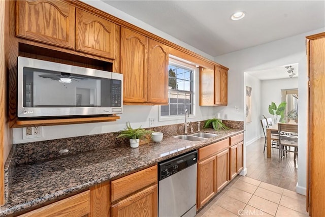 kitchen featuring sink, dark stone counters, light tile patterned floors, ceiling fan, and stainless steel appliances