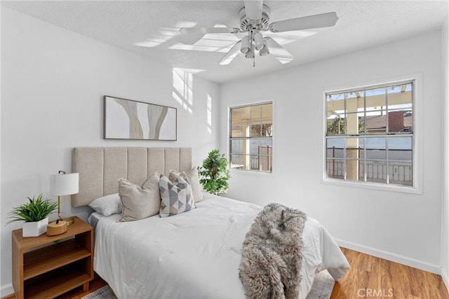 bedroom with hardwood / wood-style flooring, ceiling fan, and a textured ceiling