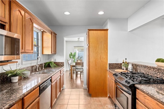 kitchen featuring appliances with stainless steel finishes, sink, dark stone countertops, and light tile patterned floors