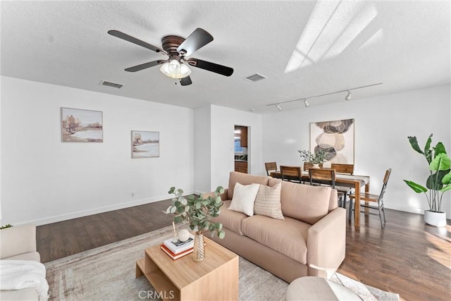 living room featuring hardwood / wood-style flooring, ceiling fan, and a textured ceiling