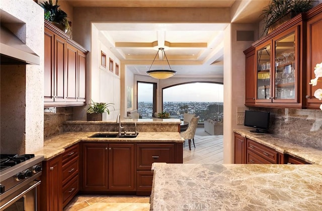 kitchen featuring decorative light fixtures, wall chimney range hood, high end range, decorative backsplash, and sink