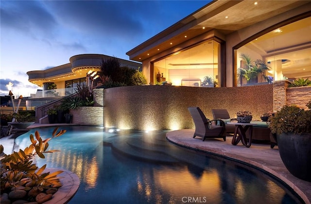 pool at dusk featuring a patio area