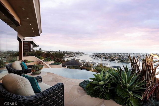 patio terrace at dusk featuring a water view