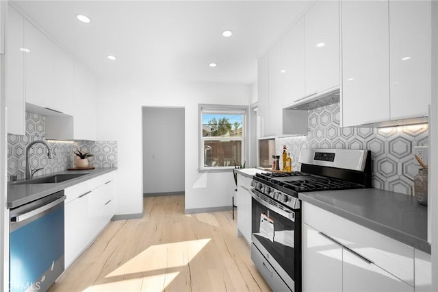 kitchen with exhaust hood, white cabinetry, stainless steel appliances, decorative backsplash, and sink