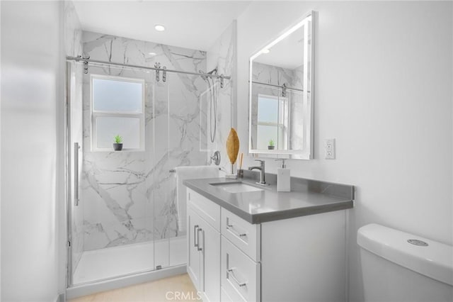 bathroom featuring toilet, a shower with shower door, and vanity