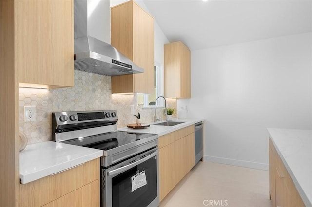 kitchen featuring appliances with stainless steel finishes, sink, light brown cabinets, and wall chimney range hood