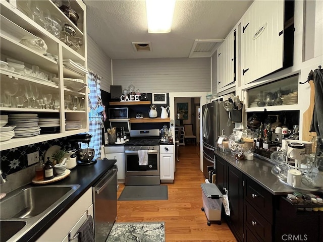 kitchen with stainless steel appliances, sink, a textured ceiling, and light hardwood / wood-style floors