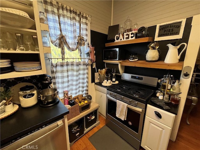 kitchen with hardwood / wood-style flooring, gas range, and white cabinets