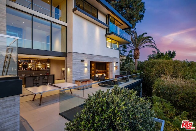 back house at dusk featuring a patio