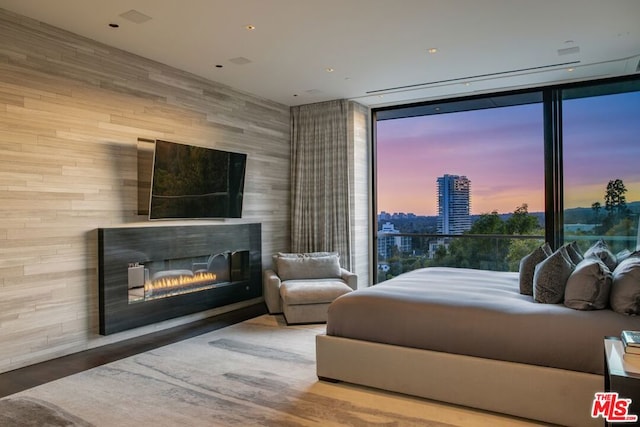 bedroom featuring a wall of windows and wood walls