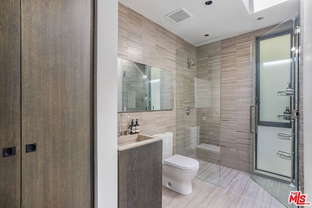 bathroom featuring toilet, a shower, tile walls, and vanity