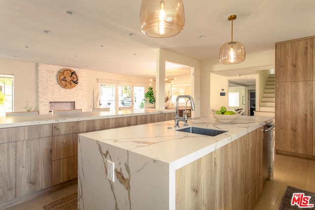 kitchen with a kitchen island with sink, a fireplace, plenty of natural light, and sink