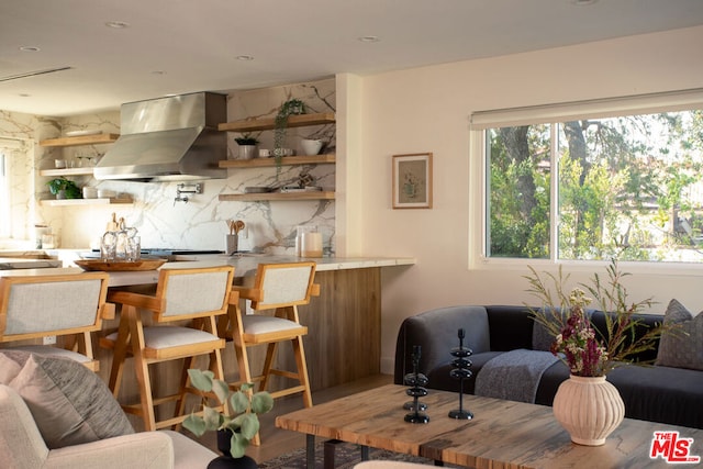 bar featuring wood-type flooring, a wealth of natural light, ventilation hood, and tasteful backsplash