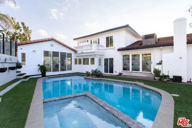 back of house featuring a lawn and a balcony