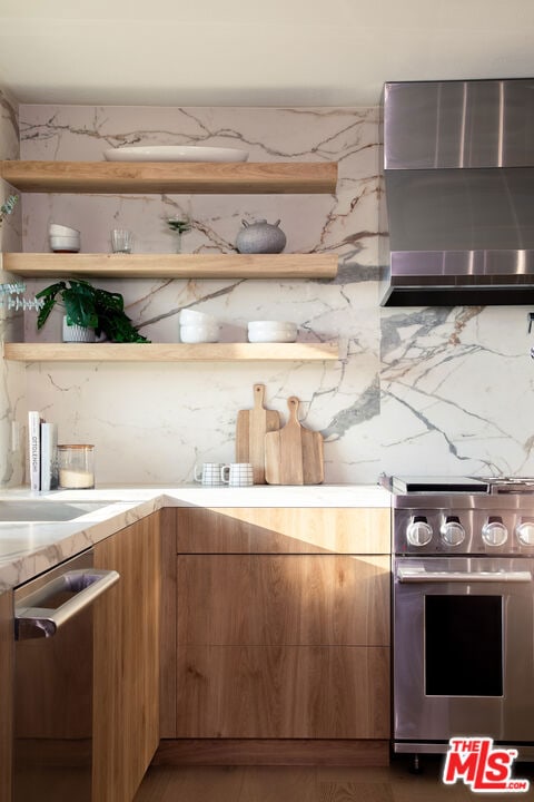 kitchen with wall chimney range hood and stainless steel appliances