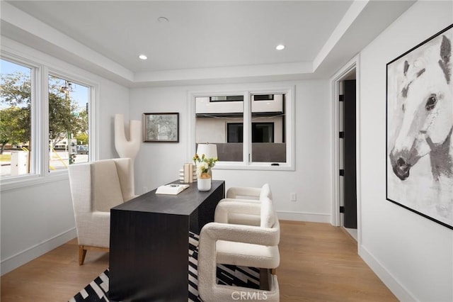 dining area with light wood-type flooring and a raised ceiling