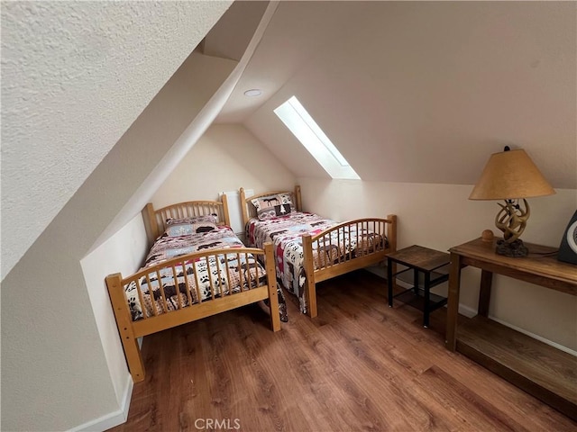 bedroom with lofted ceiling with skylight and hardwood / wood-style flooring