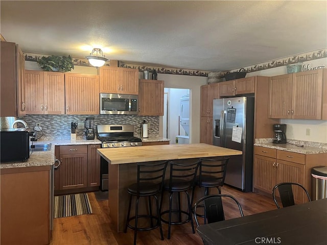 kitchen with dark wood-type flooring, stainless steel appliances, butcher block countertops, and a kitchen island