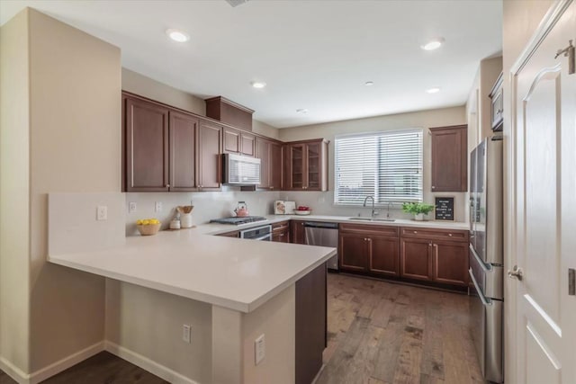 kitchen featuring kitchen peninsula, appliances with stainless steel finishes, sink, and dark hardwood / wood-style flooring