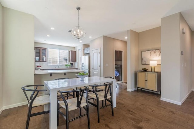 dining space featuring an inviting chandelier, dark wood-type flooring, and washer / dryer