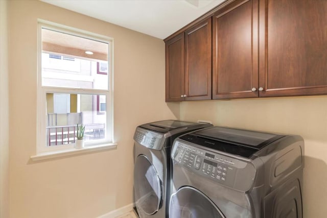 laundry room with washing machine and clothes dryer and cabinets