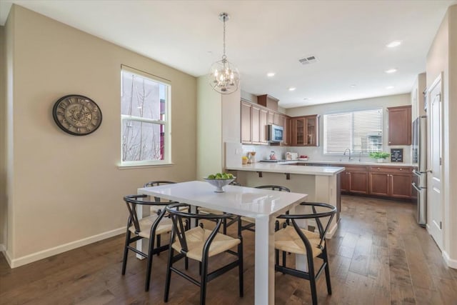 dining room featuring sink, dark hardwood / wood-style floors, a wealth of natural light, and a notable chandelier