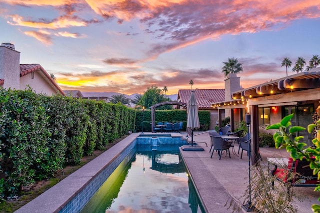 pool at dusk featuring a patio