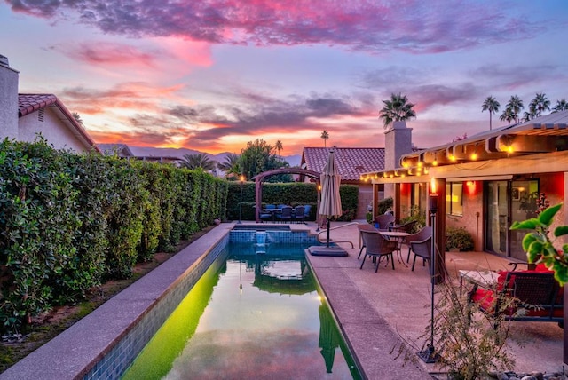 pool at dusk featuring a patio area