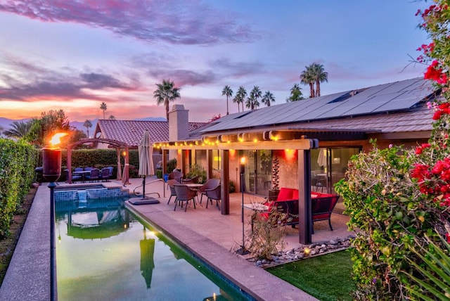 pool at dusk with an outdoor hangout area, a pergola, and a patio area