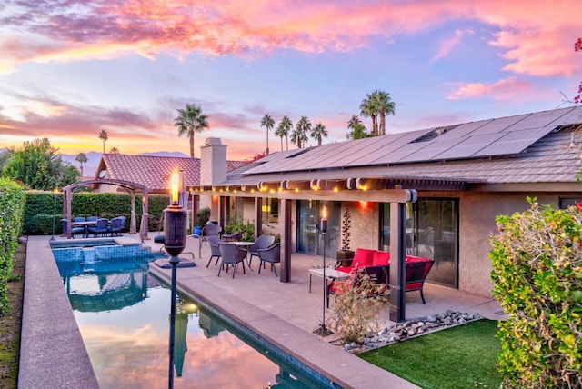 pool at dusk featuring outdoor lounge area and a patio