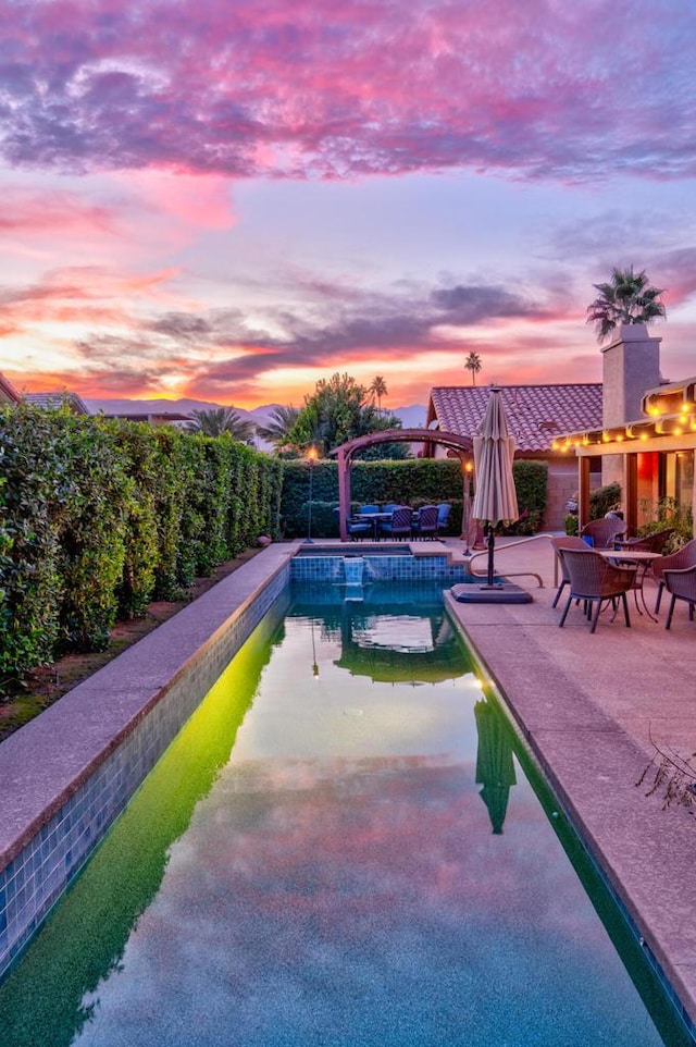 pool at dusk featuring a patio area