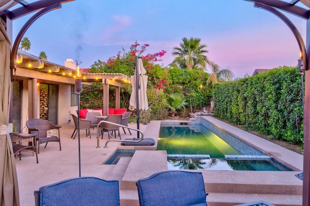 pool at dusk featuring outdoor lounge area, an in ground hot tub, and a patio