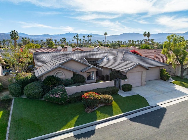 single story home with a mountain view, a front yard, and a garage