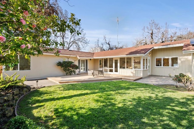 rear view of property with a sunroom, a patio area, and a yard