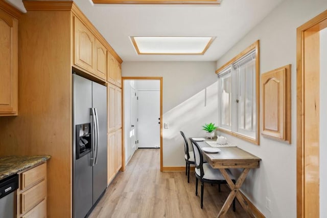 kitchen featuring light brown cabinets, light hardwood / wood-style floors, dark stone counters, and appliances with stainless steel finishes