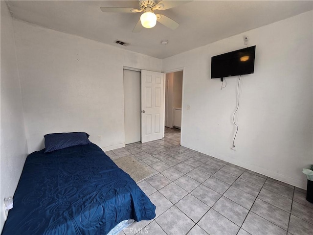 bedroom with light tile patterned flooring, ceiling fan, and a closet