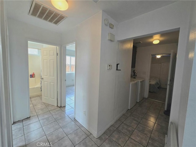 hallway featuring light tile patterned floors, independent washer and dryer, and baseboard heating