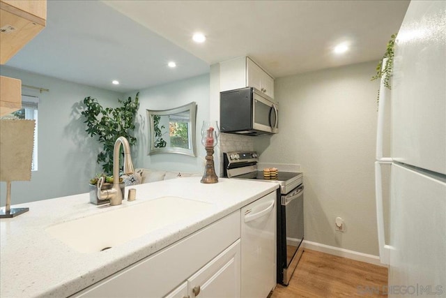 kitchen with sink, light hardwood / wood-style flooring, white cabinets, and appliances with stainless steel finishes