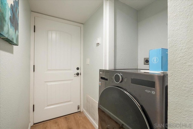 laundry area featuring washer / clothes dryer and light hardwood / wood-style flooring