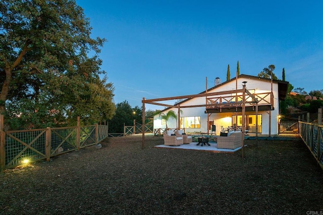 back house at dusk featuring outdoor lounge area and a patio