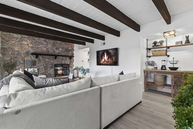 living room with light hardwood / wood-style floors, wooden ceiling, beam ceiling, and a fireplace