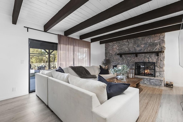 living room with beam ceiling, light wood-type flooring, a fireplace, and wooden ceiling